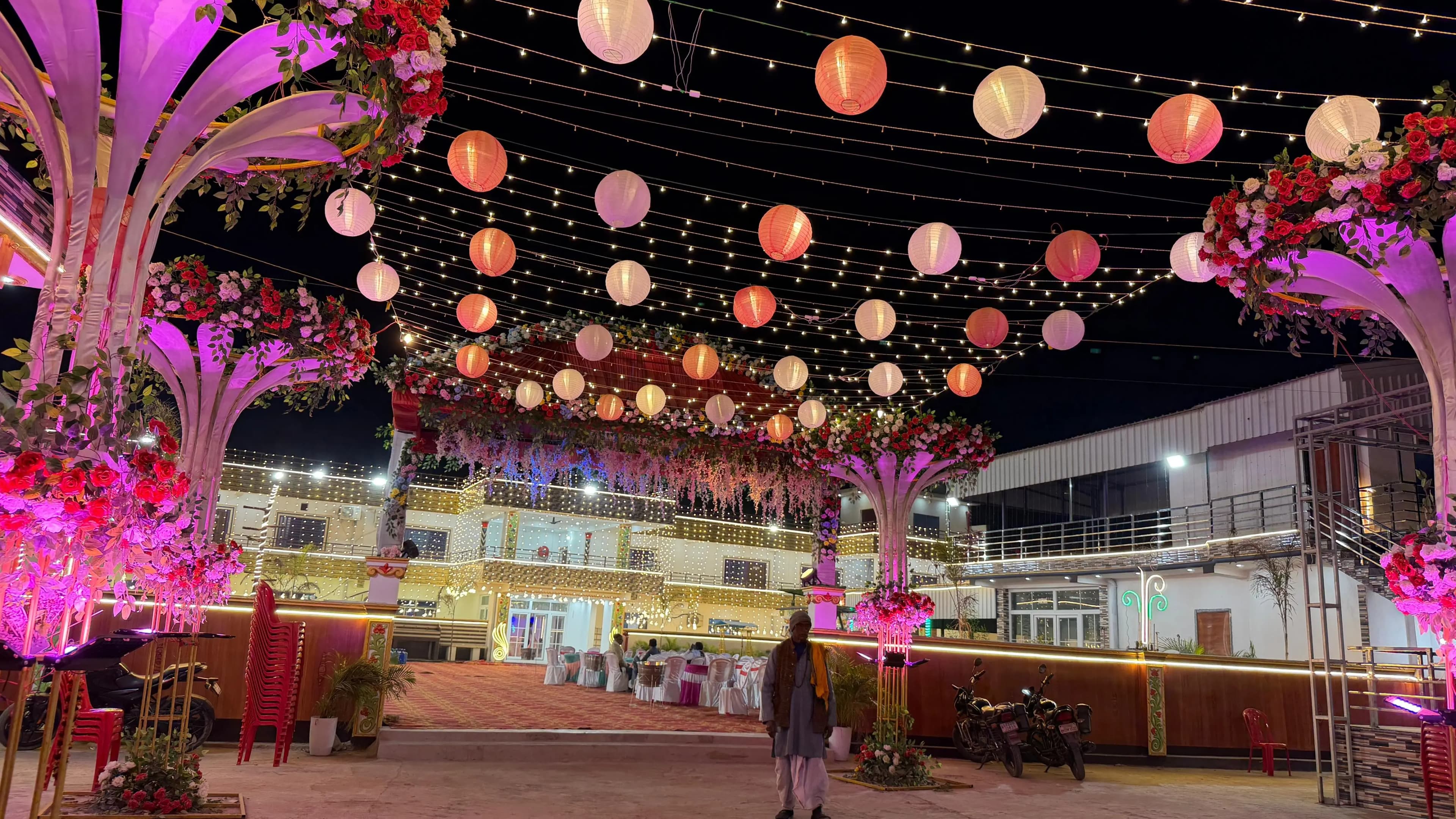 The courtyard at night beneath hundreds of hanging paper lanterns and fairy lights, with the illuminated main building at the far end