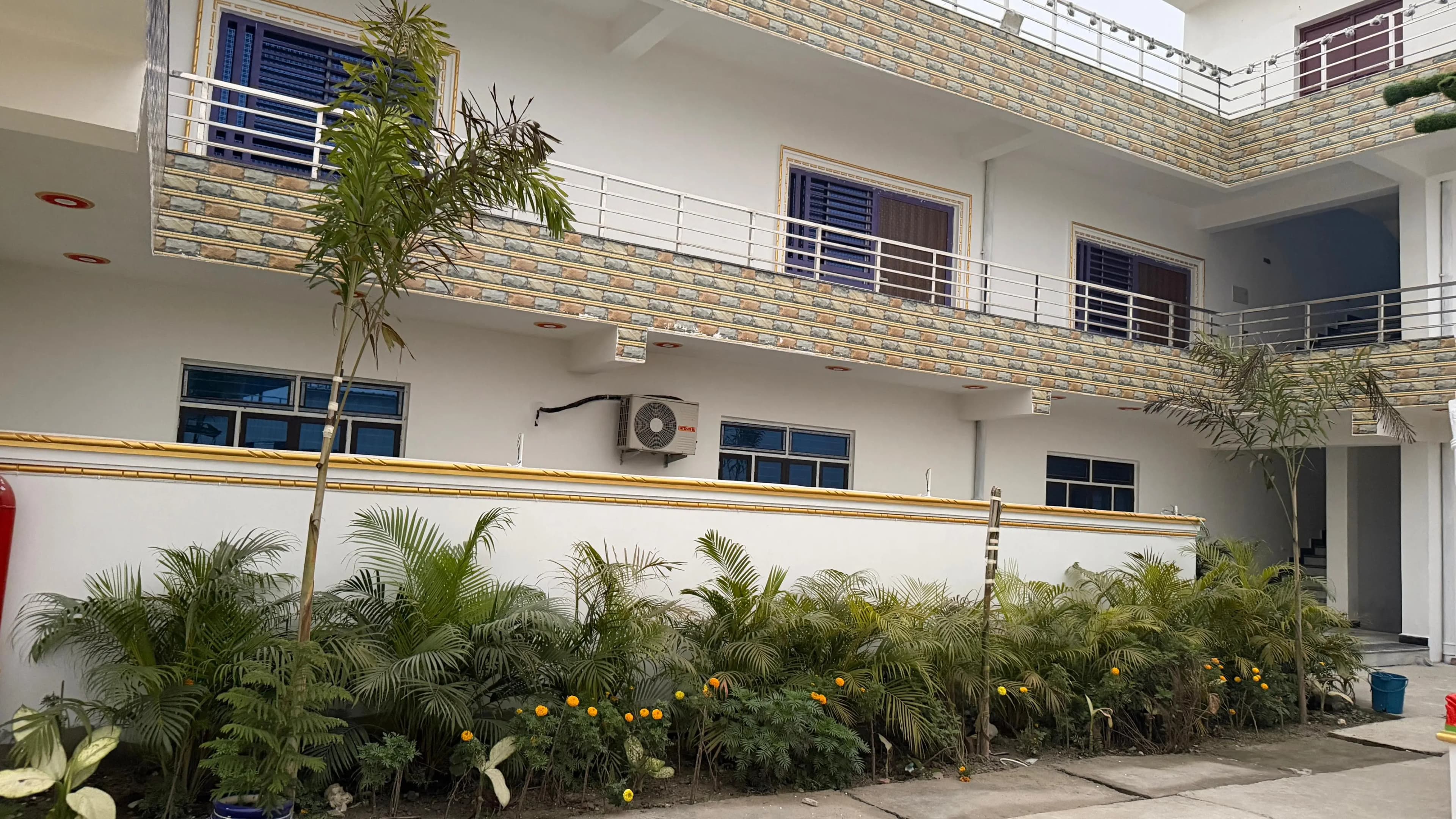 The guest-room wing in daylight, balconies above a planted border of palms and marigolds
