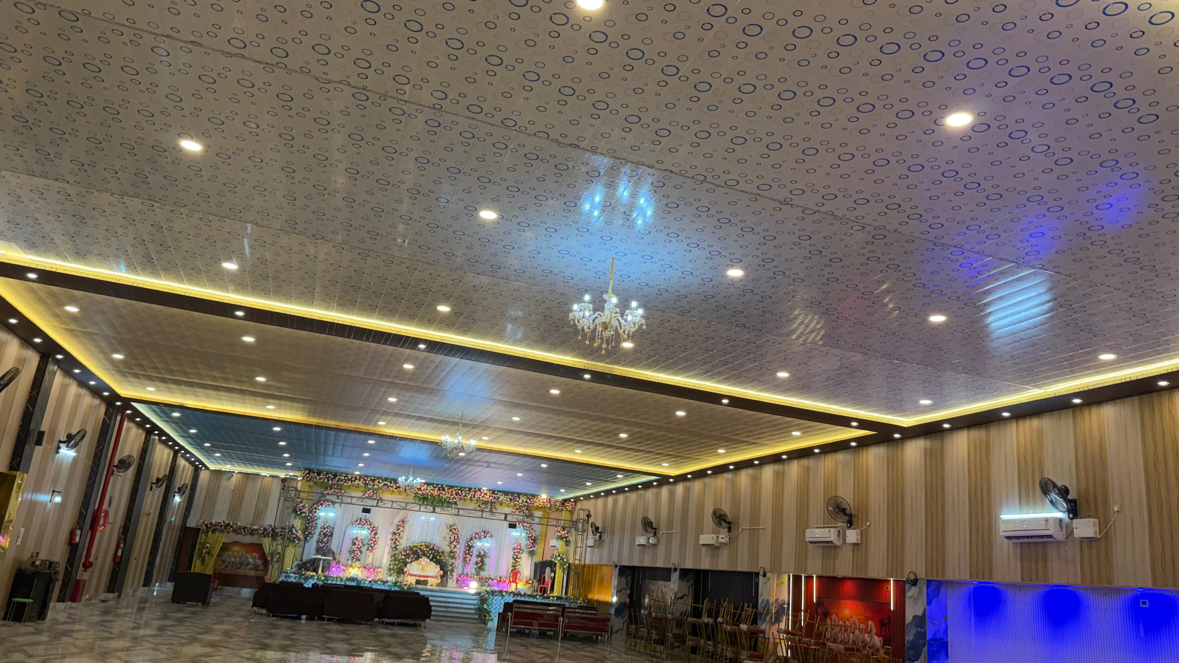 Wide view of the hall ceiling and lighting, with the decorated stage visible at the end