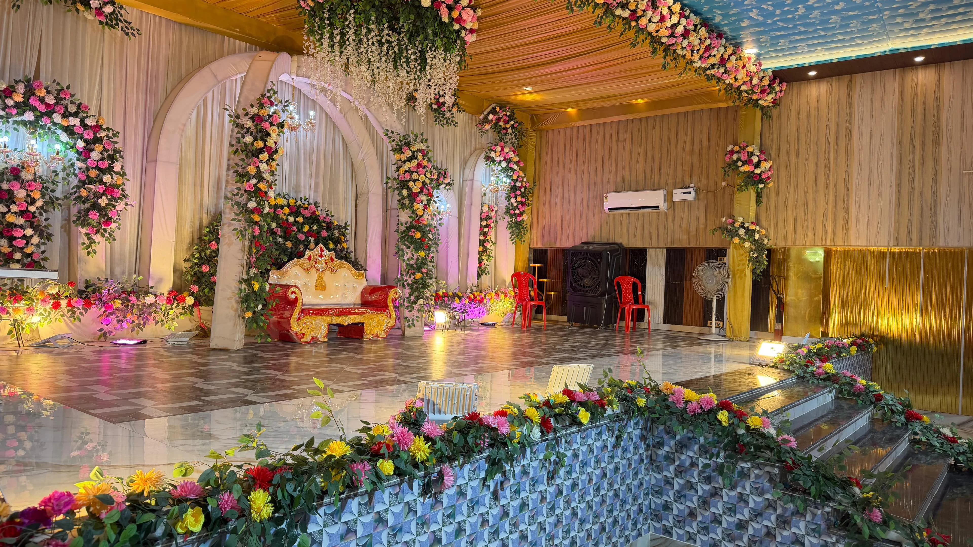 The reception stage from the side, floral arches and draped pillars beside the open marble dance floor