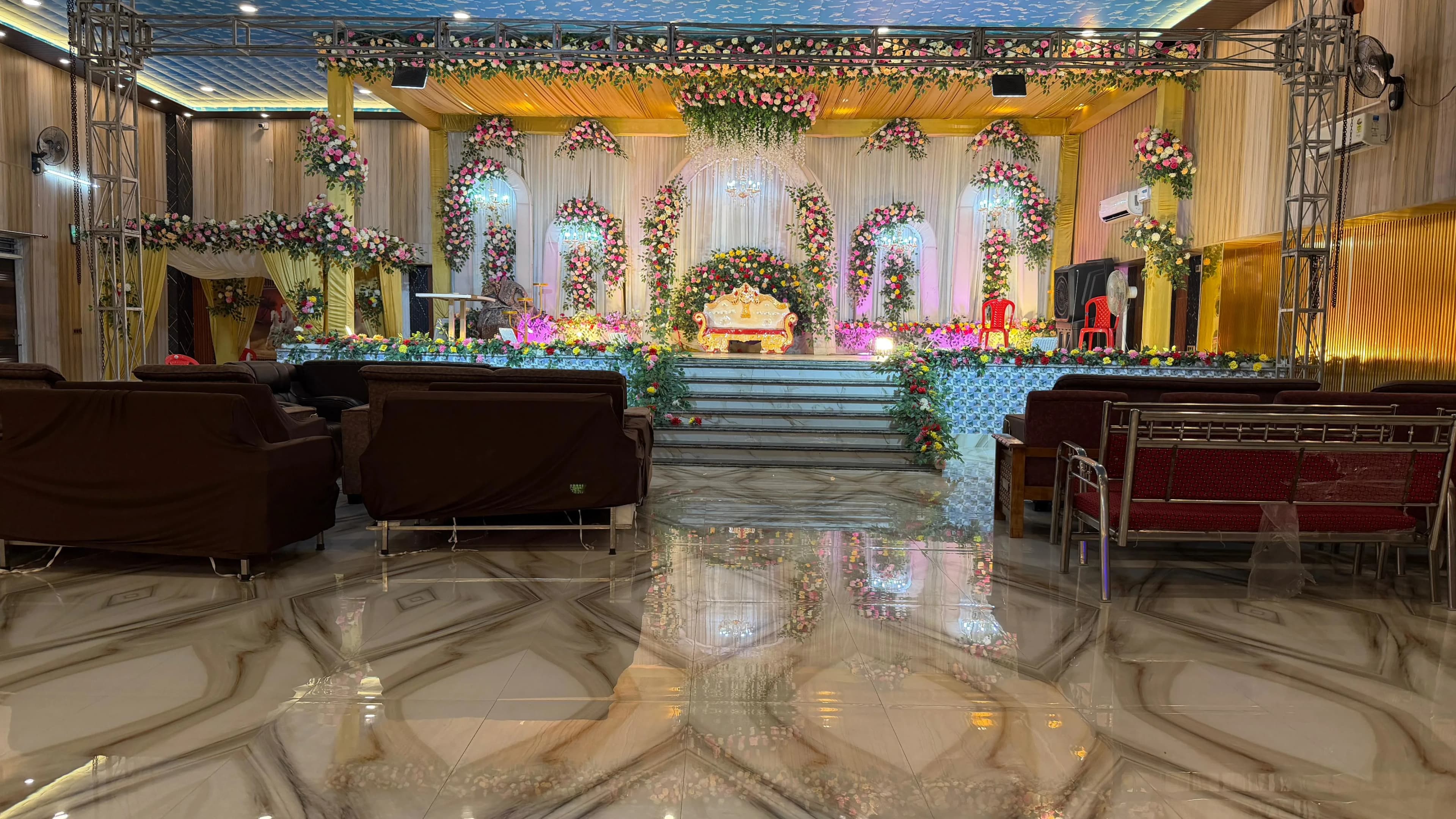 The flower-decked stage seen down the length of the hall, lounge sofas and banquet seating either side of the polished marble floor